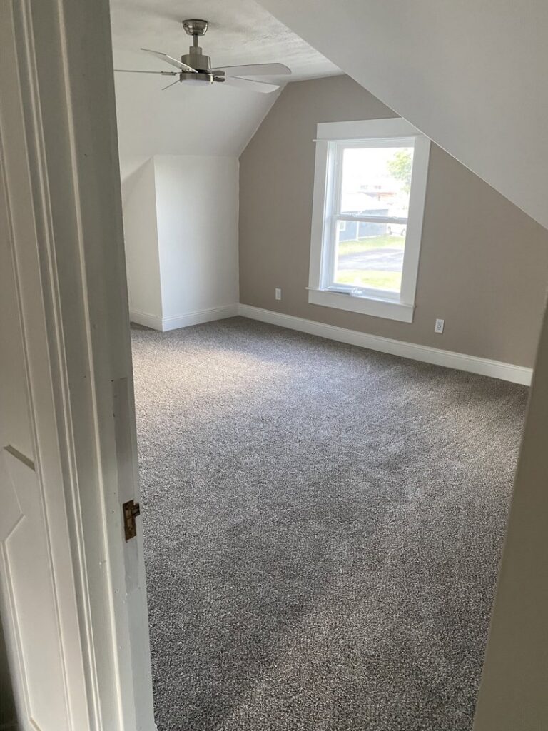 A bedroom showcasing newly installed grey carpet by Carpet Warehouse in Lafayette, IN.