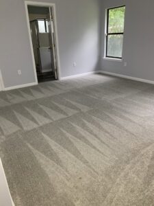 A bedroom featuring newly installed grey carpet with visible vacuum lines, completed by Gator Carpet and Tile in Jacksonville, FL.
