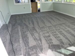 A spacious room with newly installed grey carpet, showcasing a professional finish by Floors By Tomorrow in Aurora, CO