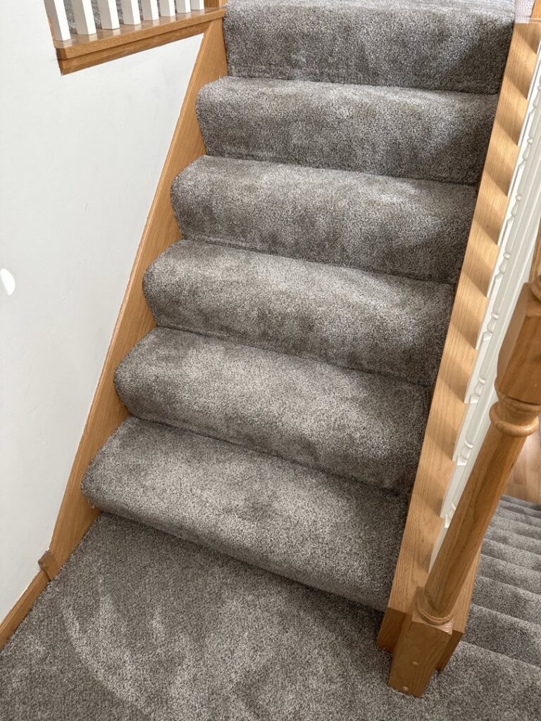 Newly installed grey carpet on a wooden staircase by Infinite Floors Kitchens Bathrooms in Burnsville, MN