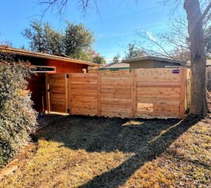 A newly installed horizontal wood fence featuring a convenient pet door, built by Stand Strong Fencing of East Austin, TX.