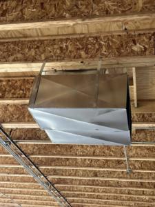 Newly installed metal HVAC ductwork hanging from a wooden ceiling structure by Airman Solutions Inc in Oklahoma City, OK