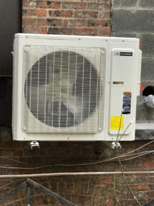 A newly installed outdoor mini-split air conditioning unit on a brick wall by L&SON Heat AC Tech in Yonkers, NY.