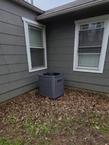 A newly installed or well-maintained outdoor air conditioning unit next to a house by Friess Heating & Air Conditioning in Topeka, KS