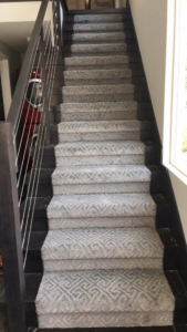 A staircase with newly installed patterned grey carpet, showcasing work by Capitol Carpet Co in Sherman Oaks, CA