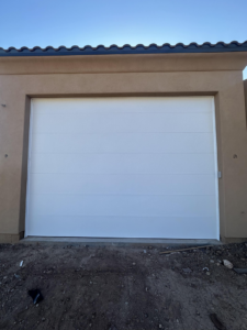 A newly installed modern white garage door on a residential home by Calavera Garage Doors in Mesa, AZ