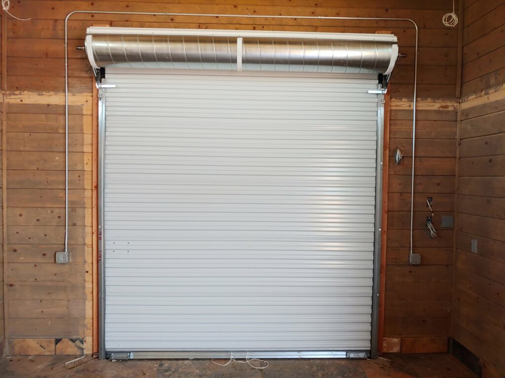 A newly installed white roll-up garage door in a wooden structure by Blue Fox Garage Doors in Gilbert, AZ.