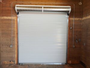 A newly installed white roll-up garage door in a wooden structure by Blue Fox Garage Doors in Gilbert, AZ.