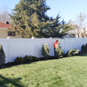 A newly installed white vinyl privacy fence in a residential backyard by Zelaya Fence in New York City, NY.