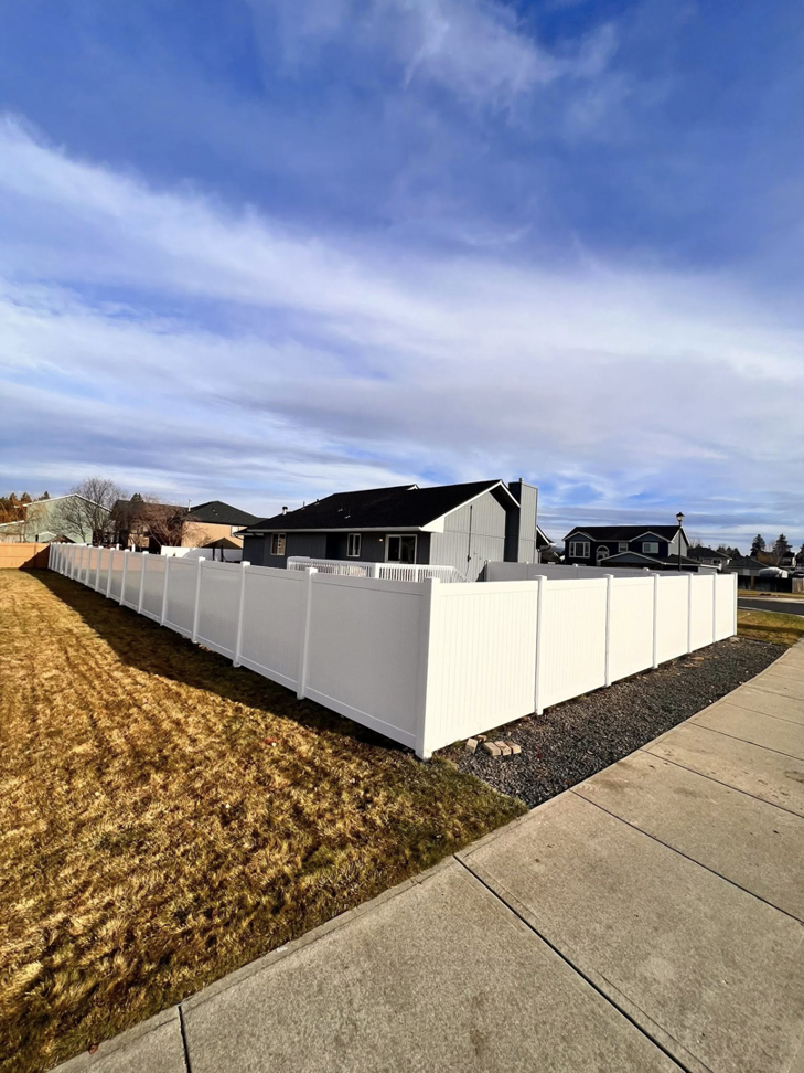 A newly installed white vinyl privacy fence surrounding a residential property by BKC Fencing in Spokane, WA.
