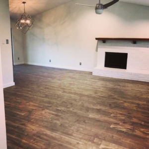 Newly installed wood-look flooring in a spacious living room by Carpet and Flooring Liquidators - Dallas in Arlington, TX.