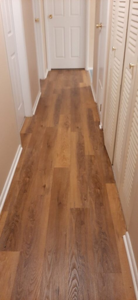 A hallway featuring newly installed wood-look flooring by Carpet Warehouse in Lafayette, IN.