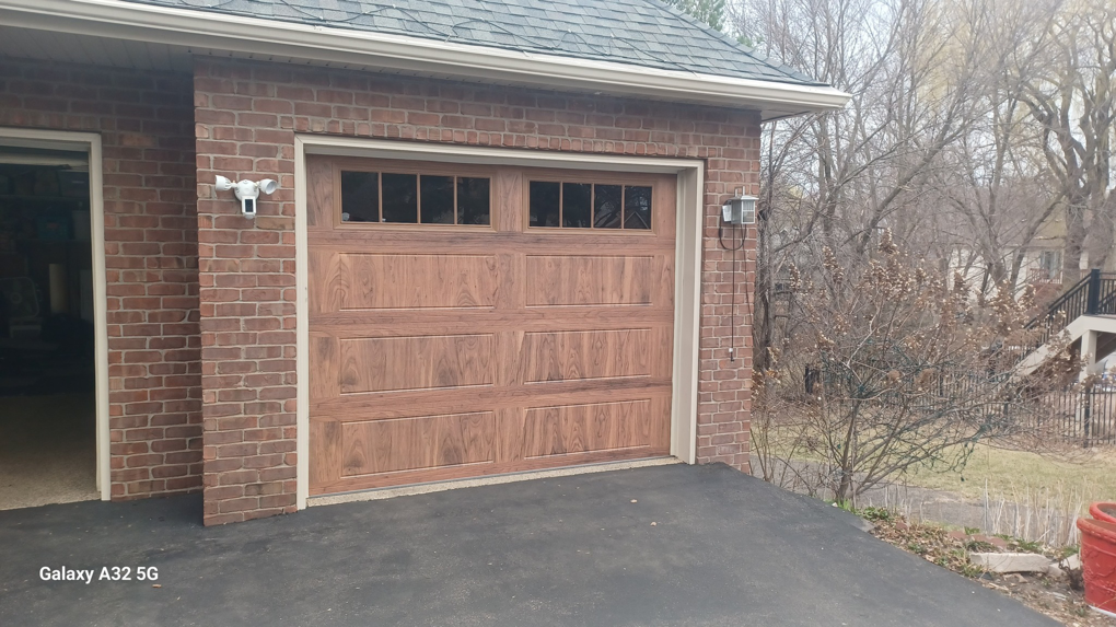 A newly installed wood-look garage door with windows, a completed project by Garage Door Technologies in Minneapolis, MN