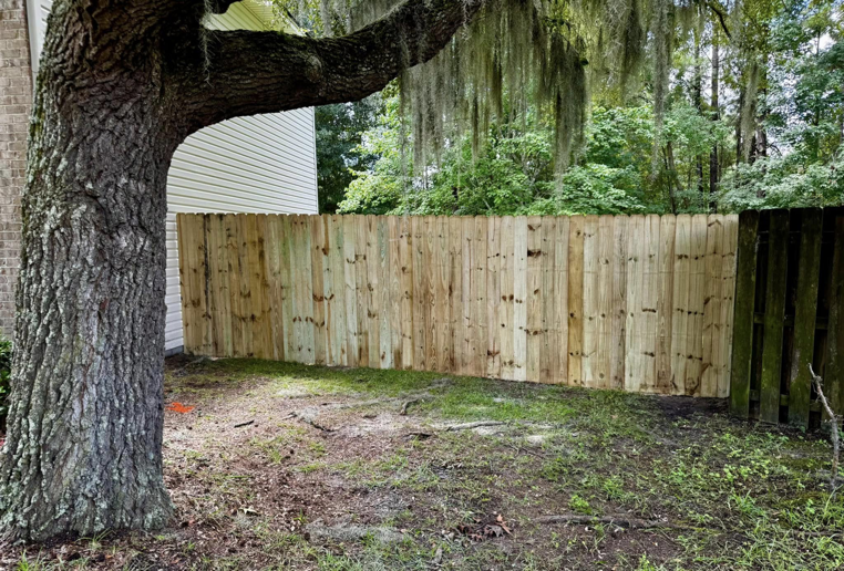 A newly installed wooden privacy fence in a backyard, completed by Barwick Fence Company in Savannah, GA.