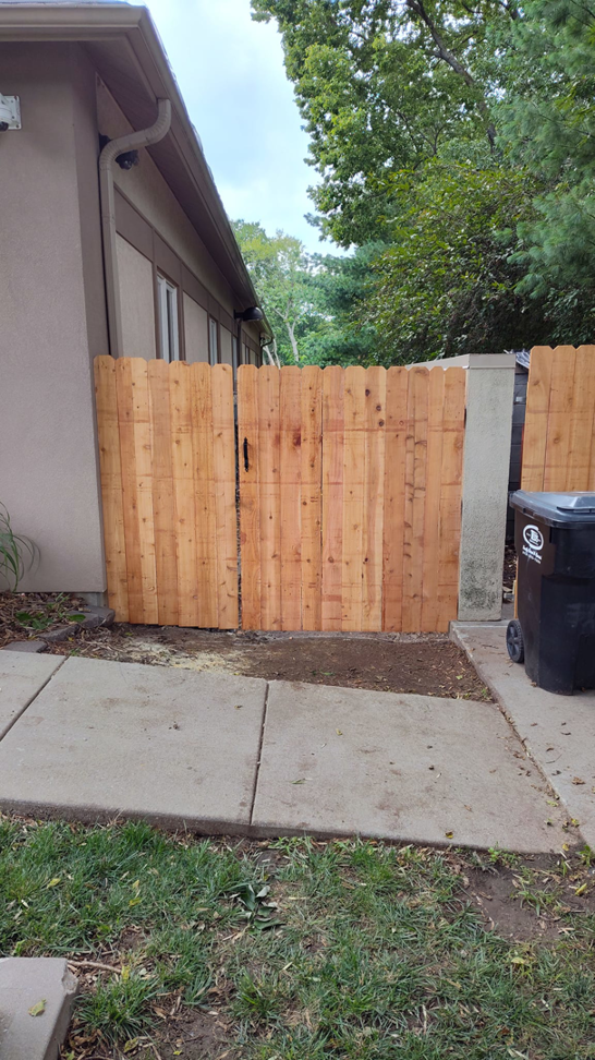 A newly installed wood privacy fence section with a gate by Lujan Fencing in Independence, MO.