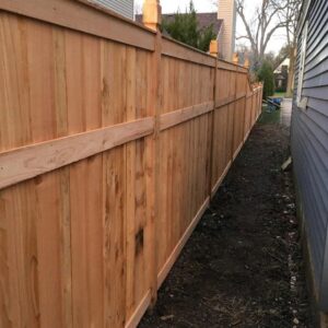 A newly installed natural wood privacy fence by Midwest Legacy Fence & Deck in Aurora, IL, separating a residential property.