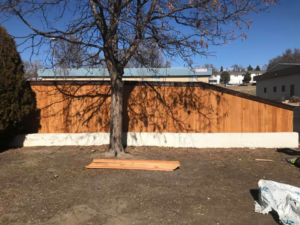 A newly installed wood privacy fence with a concrete base by Red Dirt Fencing and Woodwork, LLC in Fountain, CO.