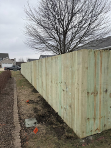 A newly installed wood privacy fence in a residential backyard by Heath's Outdoor Services LLC in Champaign, IL.