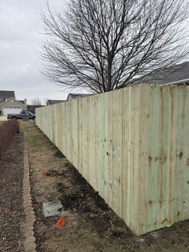 A newly installed wood privacy fence in a residential backyard by Heath's Outdoor Services LLC in Champaign, IL.