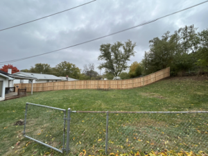A newly installed wood privacy fence curving around a residential backyard by Walker Fence in Council Bluffs, IA.