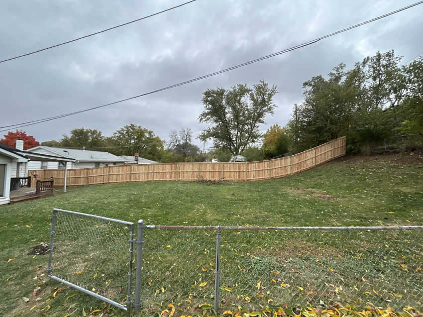 A newly installed wood privacy fence curving around a residential backyard by Walker Fence in Council Bluffs, IA.