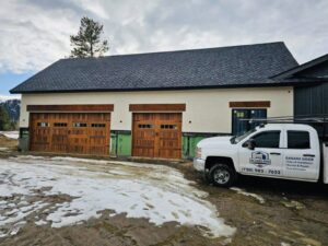 A large garage or workshop with two newly installed wooden garage doors, showcasing work by PNG Garage Doors llc in Lakewood, CO.