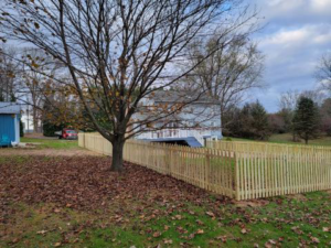 A newly installed wooden picket fence enclosing a residential yard, expertly built by Fence Fair in Baltimore, MD.
