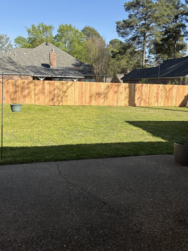 A newly installed wooden privacy fence in a residential backyard by Lynch's Temporary Fencing & Dumpster rental in Bossier City, LA.