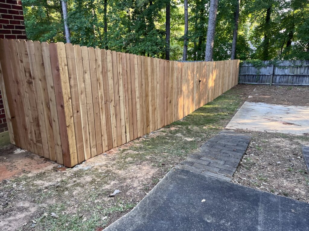 A newly installed wooden privacy fence with dog-ear pickets in a backyard by Dallas' Custom Carpentry in Alexandria, LA.