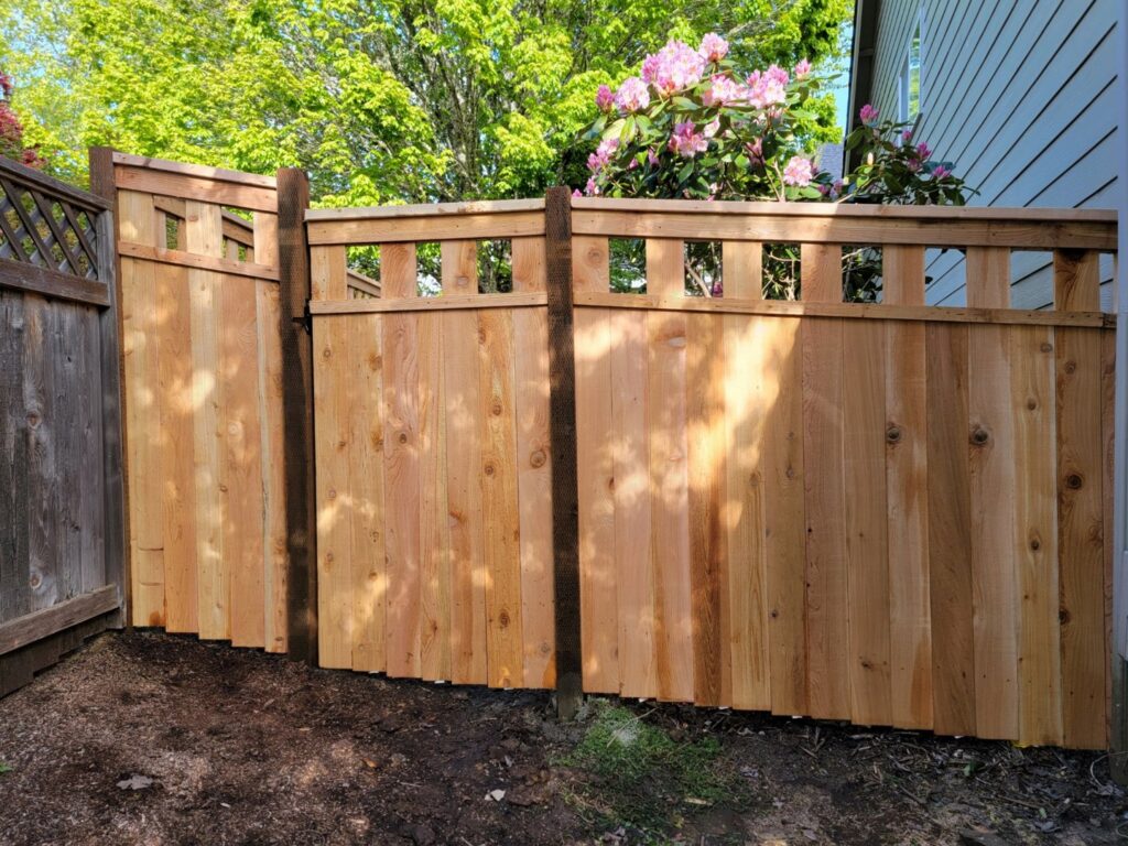 A newly installed wooden privacy fence with decorative top slats by Faxon Fencing in Corvallis, OR.