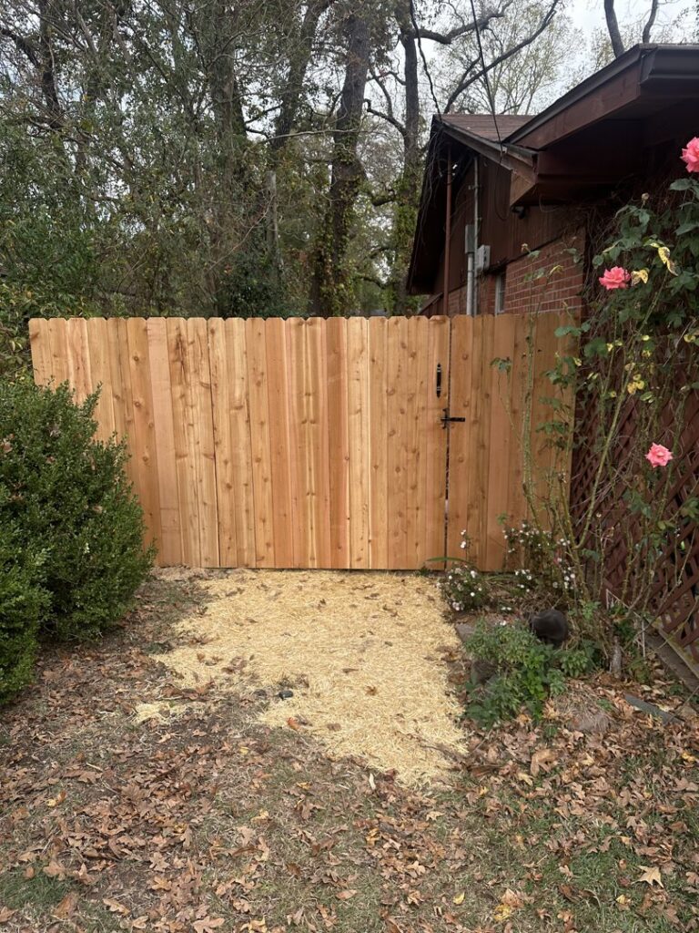A newly installed wooden privacy fence with a gate by Hometown Fence, LLC in Crawfordville, FL