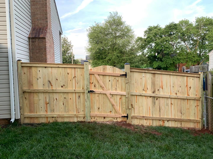 A newly installed wooden privacy fence with a gate, showcasing quality work by Arias Fence & Repair in Manassas, VA.