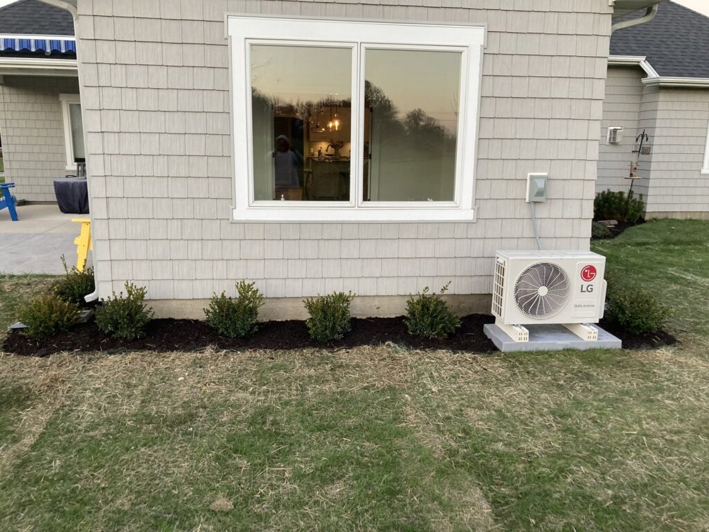 Newly mulched flower beds with small green bushes planted along the side of a house by Three Rivers Lawn Care Co. in Fort Wayne, IN.