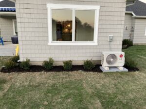Newly mulched flower beds with small green bushes planted along the side of a house by Three Rivers Lawn Care Co. in Fort Wayne, IN.