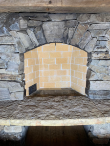 A newly rebuilt fireplace firebox with a stone surround by The Chimney Sweep in Stafford, VA.
