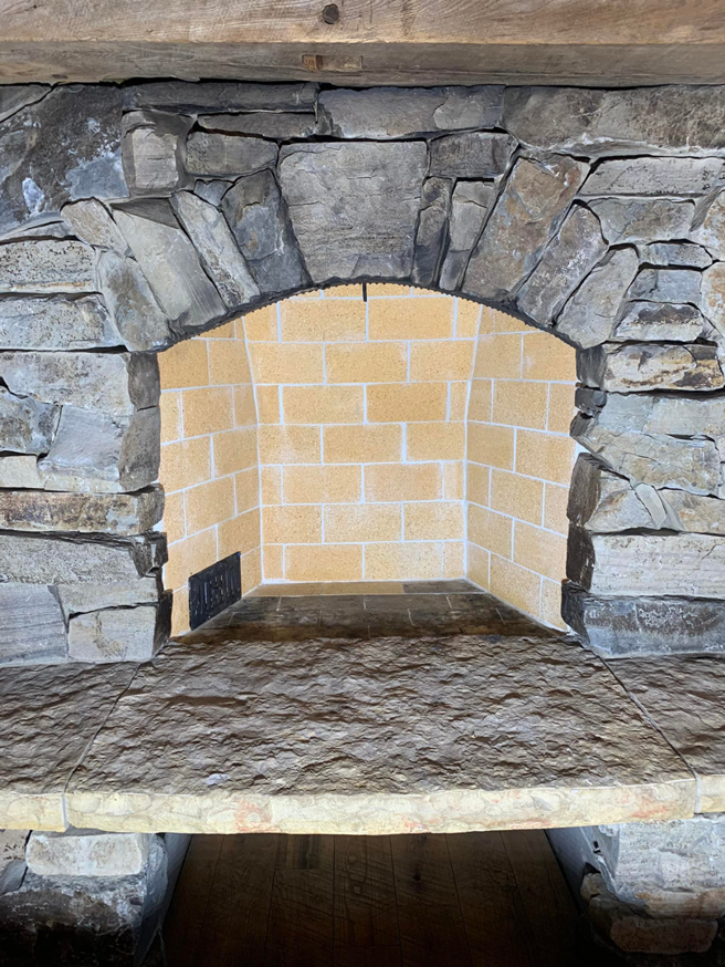 A newly rebuilt fireplace firebox with a stone surround by The Chimney Sweep in Stafford, VA.