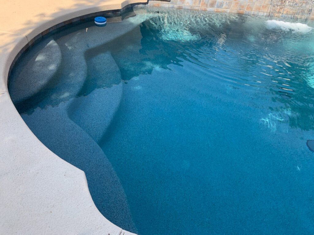 A newly renovated swimming pool with a dark blue finish and steps, completed by East Mesa Pools, LLC in Mesa, AZ.
