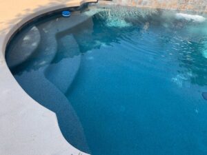 A newly renovated swimming pool with a dark blue finish and steps, completed by East Mesa Pools, LLC in Mesa, AZ.