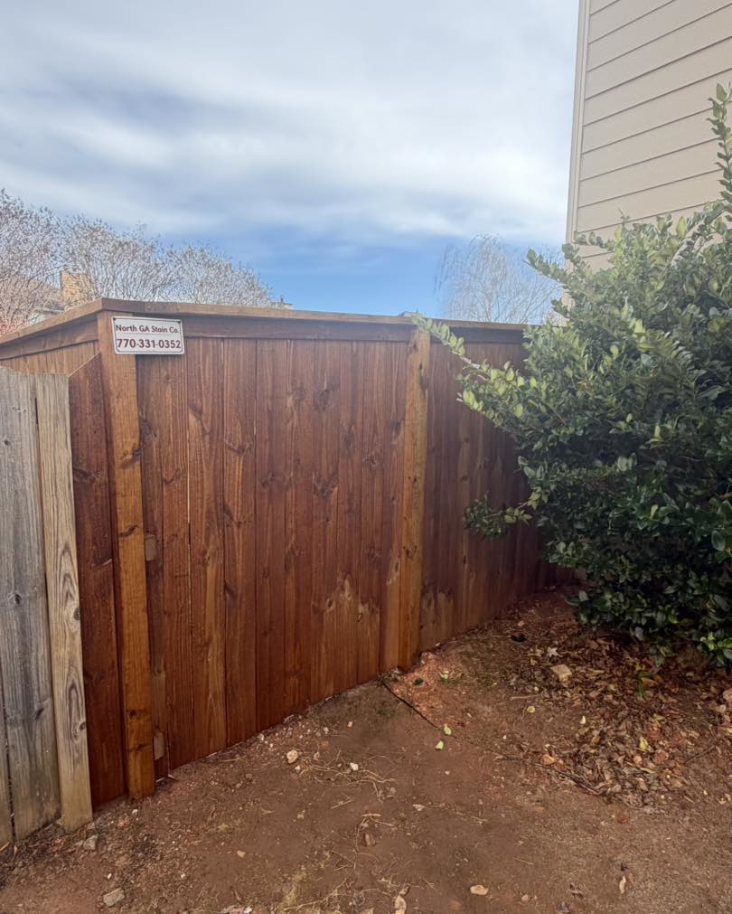 A section of a newly stained wooden fence, showcasing quality work by North GA Stain Co. in Cumming, GA.