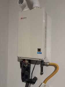 A newly installed Noritz tankless water heater with pipes by Hendrix Heating & Air in Newport News, VA.