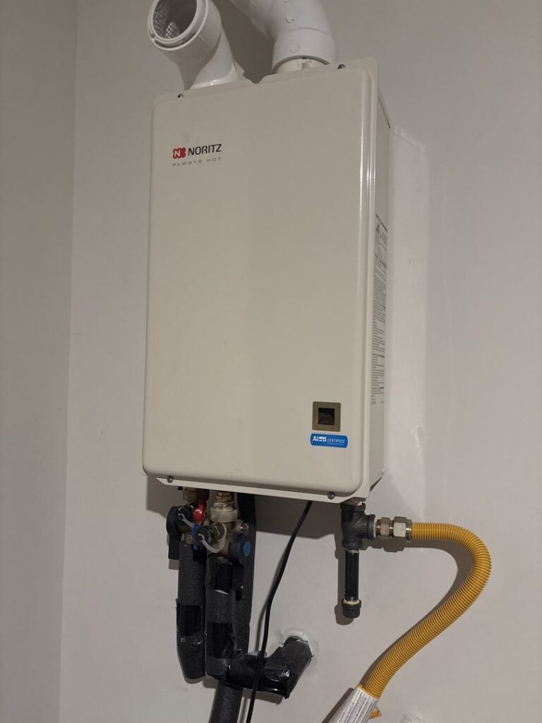 A newly installed Noritz tankless water heater with pipes by Hendrix Heating & Air in Newport News, VA.