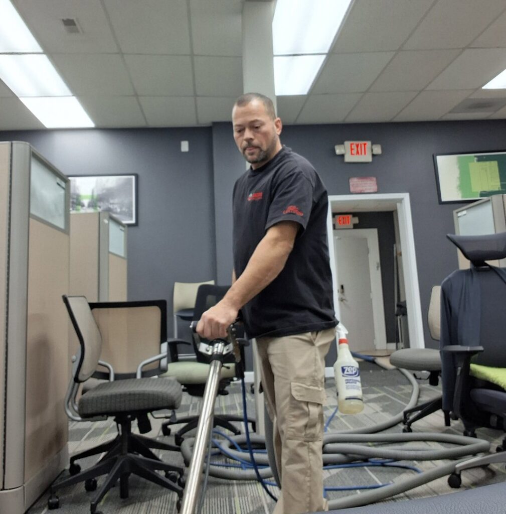 A technician cleaning office carpet in a commercial workspace by Advanced Carpet Cleaning in College Station, TX