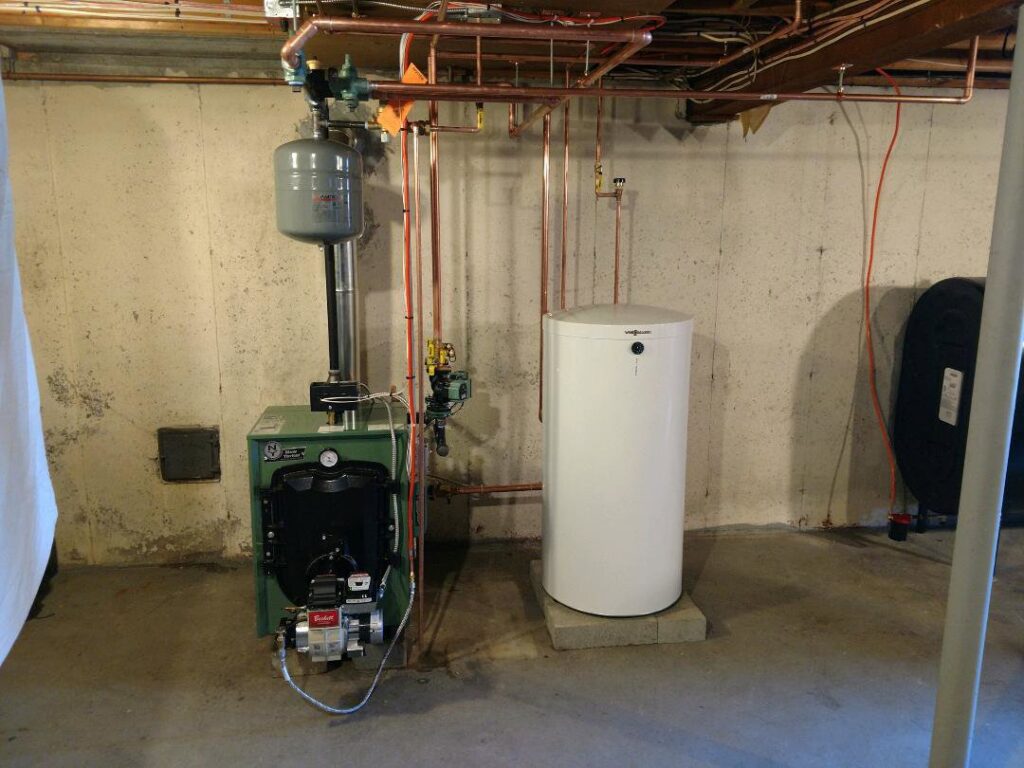 An oil burner service installation showing a green boiler and a white water heater by Nate's Oil Burner Service in New Bedford, MA
