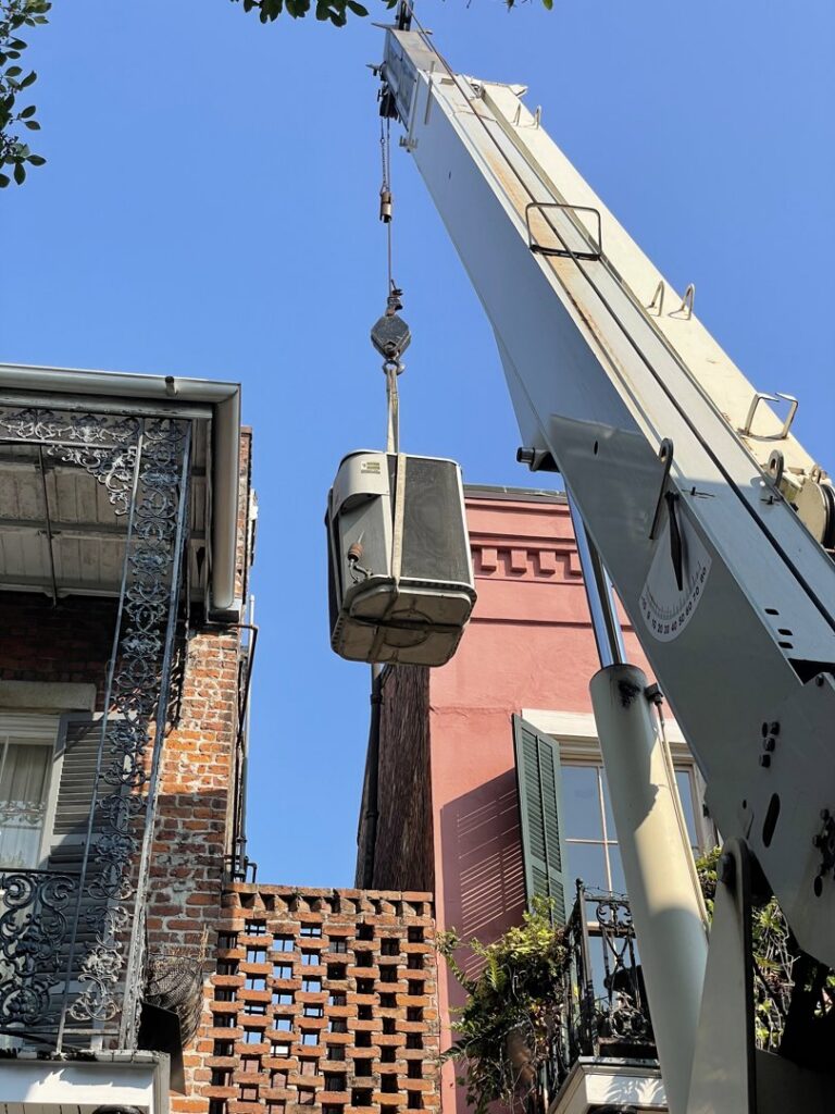 An old AC unit being removed by a crane for Caballero's A/C & Heating in Marrero, LA.