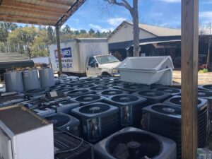 A collection of old outdoor AC units and water heaters ready for disposal by Cooler Solutions LLC Heating & Air in Gulfport, MS.