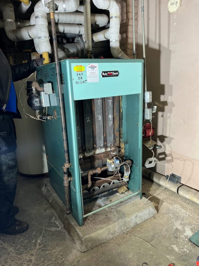 An old boiler or furnace with its front panel removed for service by Done Right Air in West Allis, WI