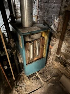 An old boiler or furnace unit in a basement, likely undergoing inspection by ECA DuctWorks in Reston, VA