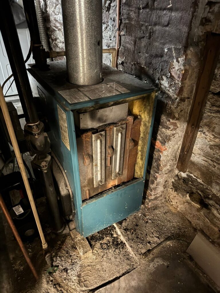An old boiler or furnace unit in a basement, likely undergoing inspection by ECA DuctWorks in Reston, VA