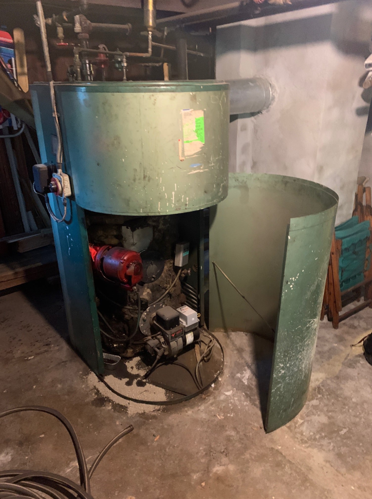 An old boiler or furnace unit in a basement, ready for replacement by Tony Marzano Plumbing & Heating LLC in Hartford, CT.
