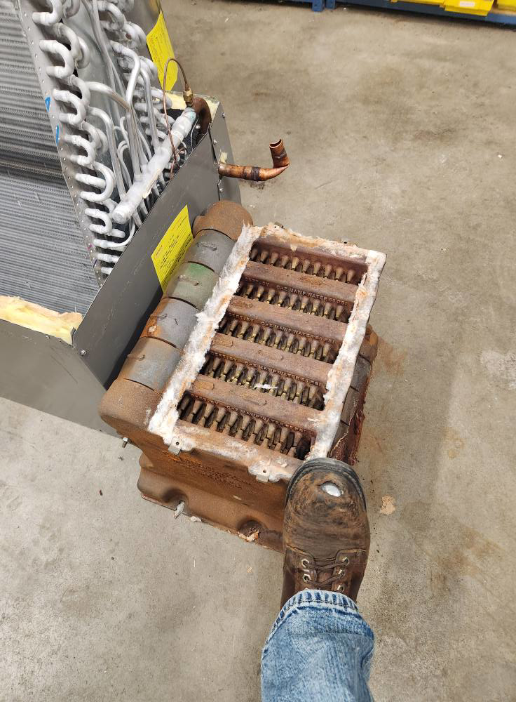 An old, rusty boiler or heat exchanger unit next to a new coil, indicating HVAC repair or replacement by Hvaclife in Minneapolis, MN.